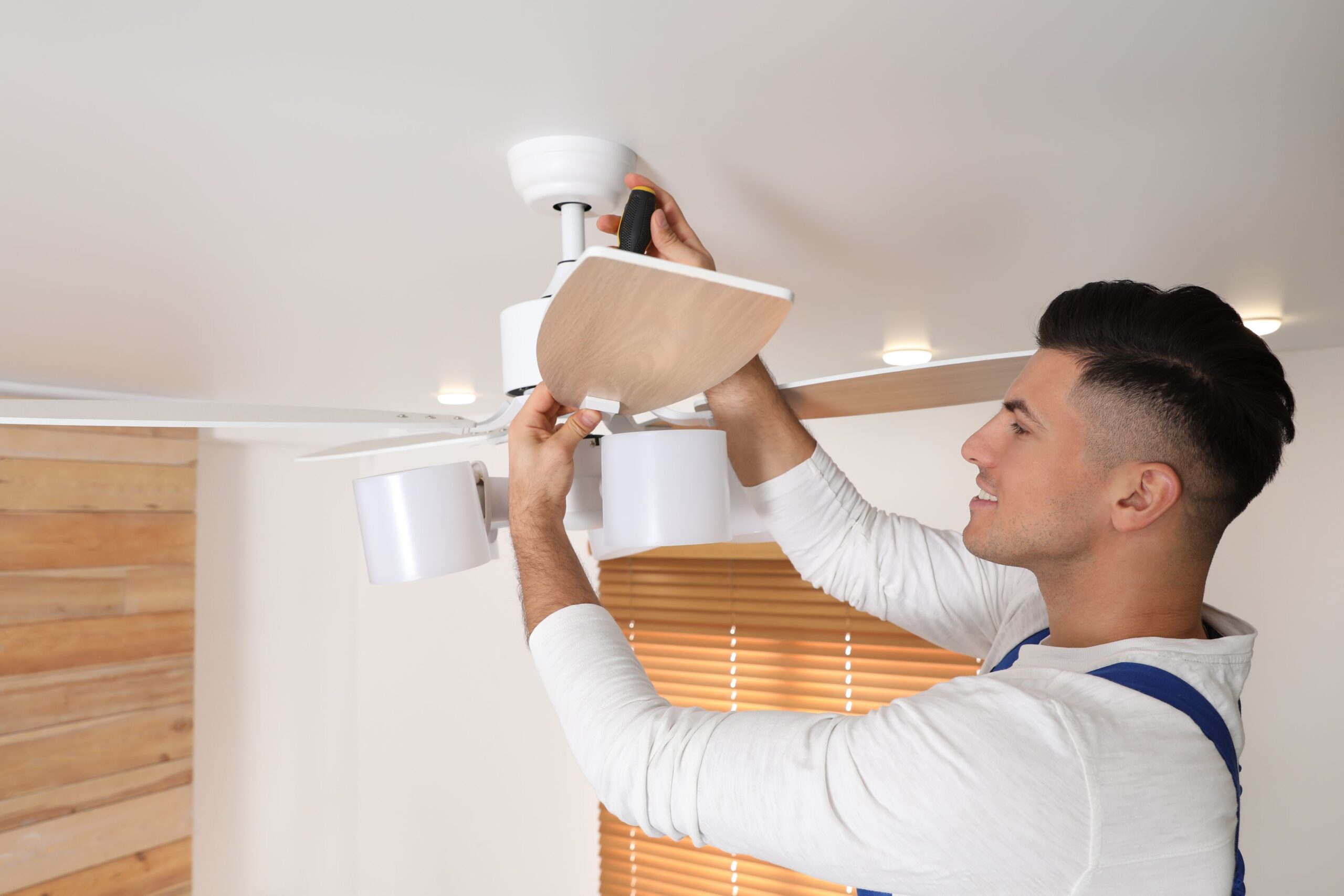 Depositphotos resize A man installing a ceiling fan in a room.  scaled