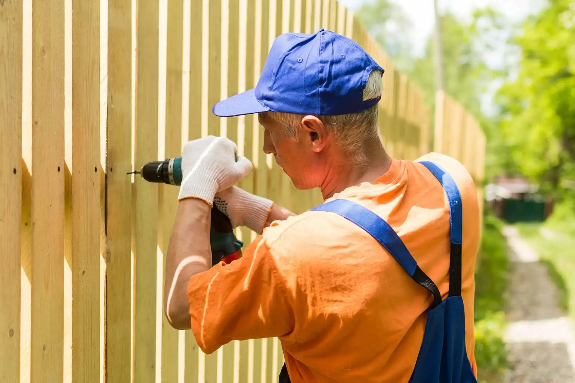 A repairman is repairing a fence