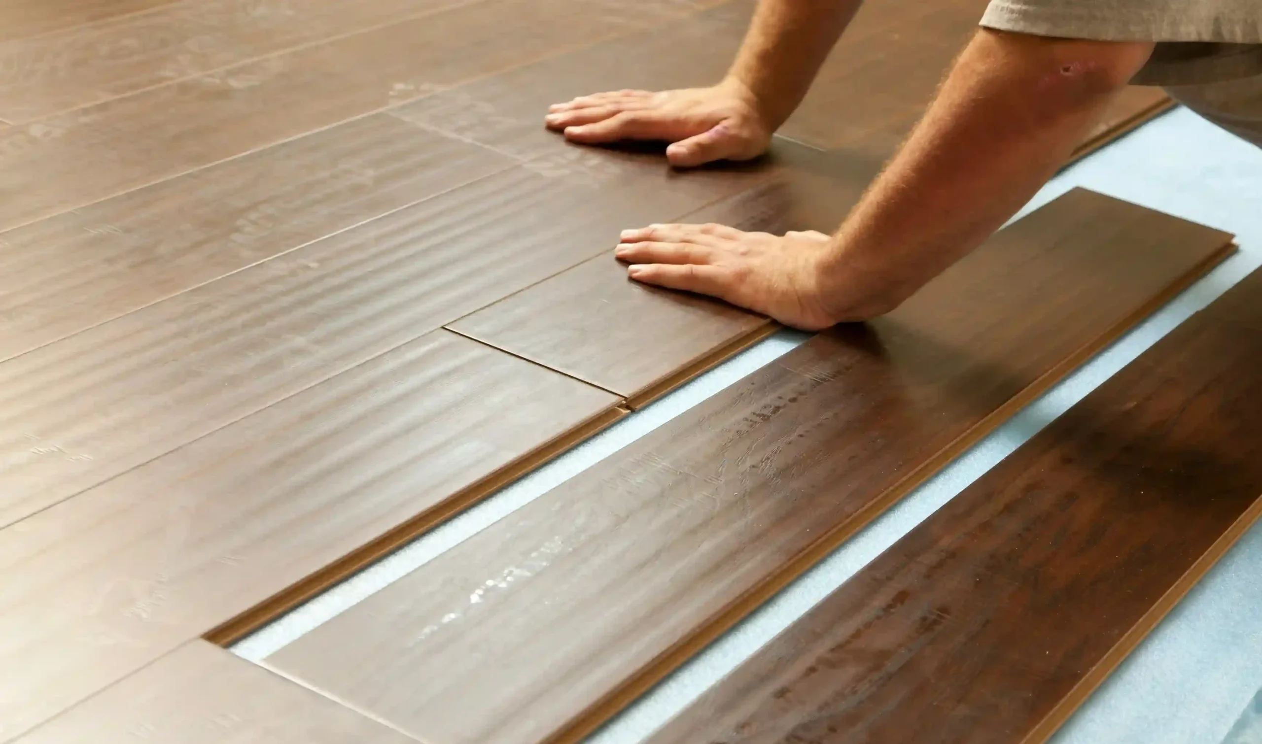 TJ Handyman Services professional installing dark wood-look flooring planks over underlayment in an Orlando home.